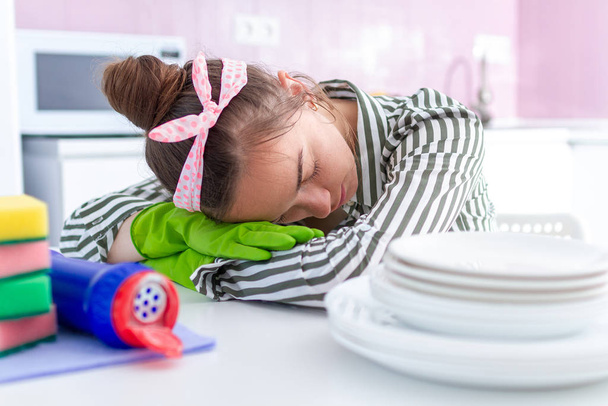Tired overworked housewife fell asleep and resting on the table because of housekeeping fatigue from spring cleaning and hard household chores  - 写真・画像