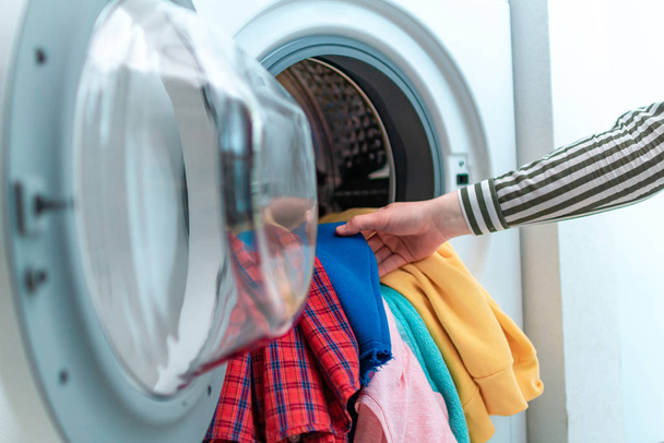 Loading colored clothes and linen in washing machine. Doing laundry at home  - Foto, immagini
