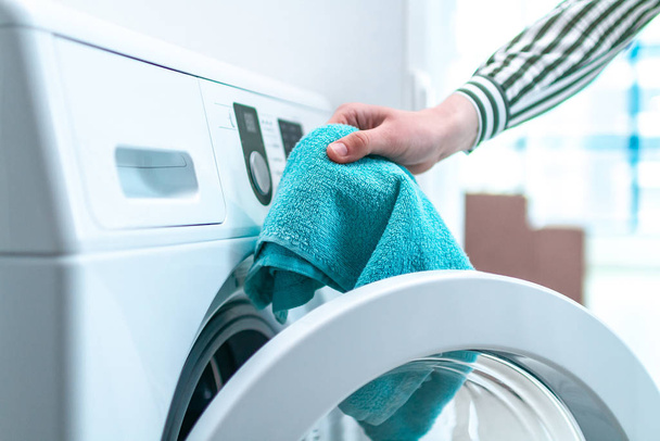 Loading towel, clothes and linen in washing machine. Doing laundry at home. Household chores and housekeeping - Foto, Imagen