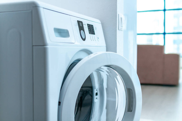 Modern washing machine in room in apartment. Doing laundry at home  - Valokuva, kuva