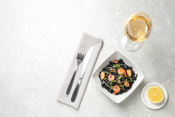 Delicious black risotto with seafood served on light grey marble table. Space for text - 写真・画像
