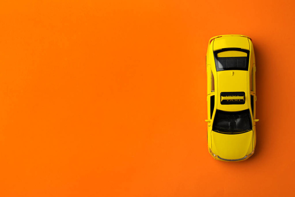 Yellow taxi car model on orange background, top view. Space for text - Foto, Bild