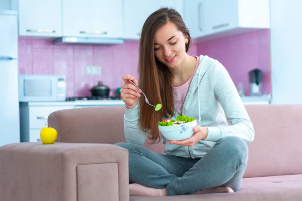 Young happy vegan woman eating vegetable salad for lunch at home. Diet and fitness eating. Clean and healthy food  - Foto, Imagem