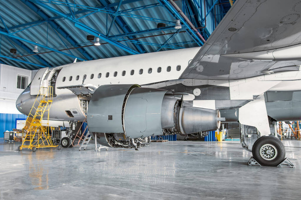 Keskeny karosszériájú utasszállító légi járművek karbantartása a hangárban, a motor oldalnézete és a futómű. - Fotó, kép