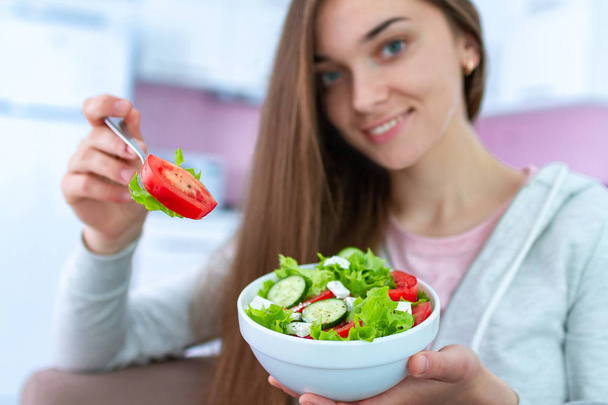 Egy fiatal, boldog, egészséges nő portréja, aki friss zöldségsalátát eszik otthon. Kiegyensúlyozott diéta és fitnesz evés. Tiszta és ellenőrizhető élelmiszerek  - Fotó, kép