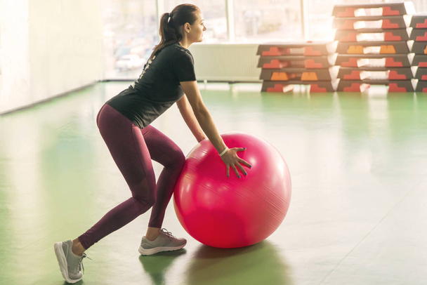 Женщина в спортзале делает упражнения с мячом для пилатеса
 - Фото, изображение