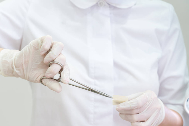 Médico usando guantes con pinzas quirúrgicaspara abrir la banda de ayuda
 - Foto, imagen