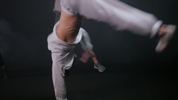 Jongeman het uitvoeren van break dancing truc - vrouwen dansen op de achtergrond - Video