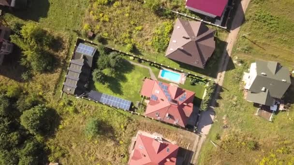 Luchtfoto van een nieuw autonoom huis met zonnepanelen en waterverwarming radiatoren op het dak en groene tuin met blauw zwembad. - Video