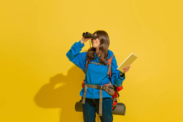 Full length portrait of a cheerful young caucasian tourist girl isolated on yellow background - Fotoğraf, Görsel