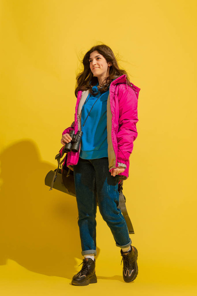 Full length portrait of a cheerful young caucasian tourist girl isolated on yellow background - Zdjęcie, obraz