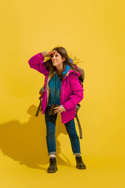 Full length portrait of a cheerful young caucasian tourist girl isolated on yellow background - Foto, Bild