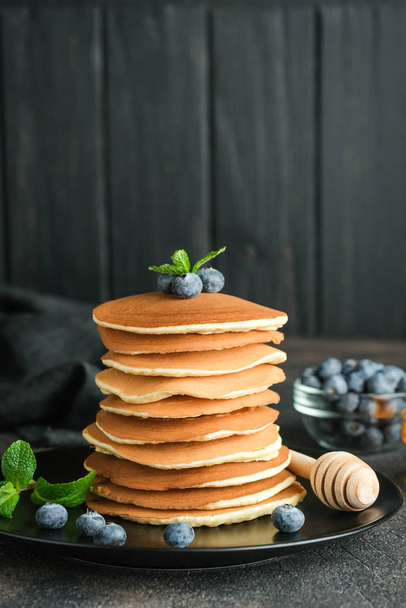 Delicious pancakes, with fresh blueberries, strawberries and caramel on a dark background. - Foto, Imagen