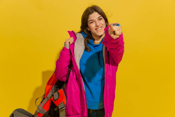 Portrait of a cheerful young caucasian tourist girl isolated on yellow background - Photo, Image