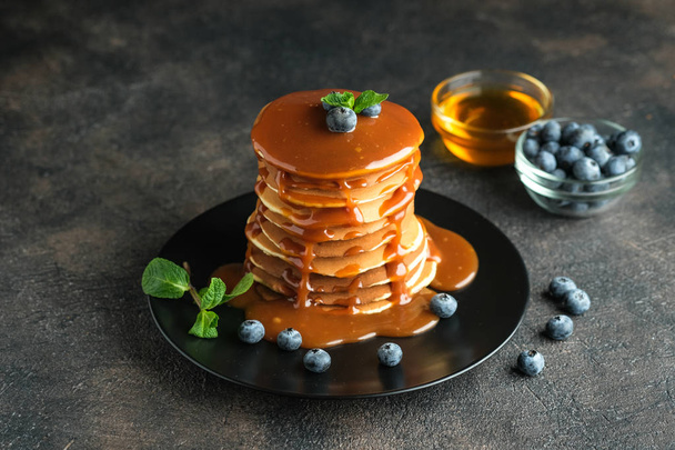 Delicious pancakes, with fresh blueberries, strawberries and caramel on a dark background. - Photo, Image