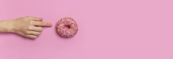 Belas mãos femininas com manicure suave segurar donut doce no fundo rosa vista superior plana colocar espaço de cópia. Unhas naturais, gel polonês, autocuidado, beleza e moda. Cuidados com unhas. Fundo Donut
 - Foto, Imagem