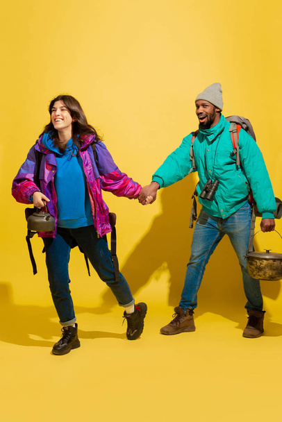 Portrait of a cheerful young tourist couple isolated on yellow background - Фото, зображення