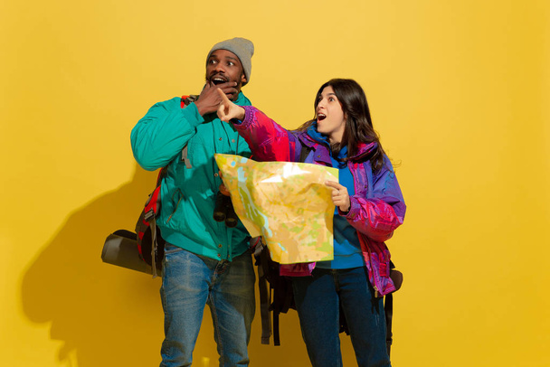 Portrait of a cheerful young tourist couple isolated on yellow background - Foto, Bild