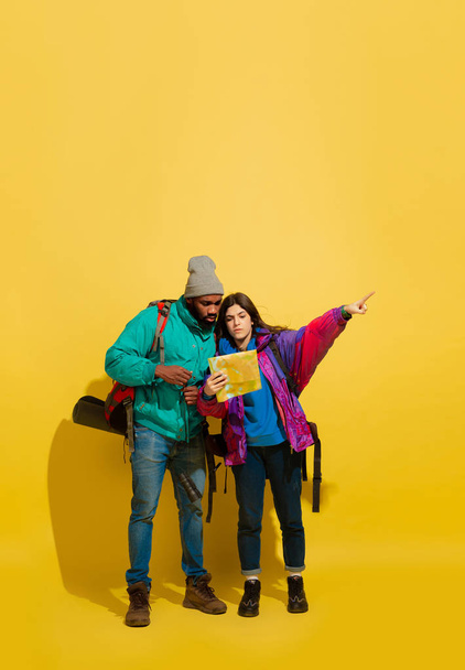 Portrait of a cheerful young tourist couple isolated on yellow background - Foto, Imagen