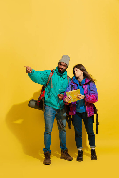 Portrait of a cheerful young tourist couple isolated on yellow background - Фото, изображение