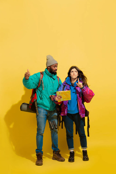 Portrait of a cheerful young tourist couple isolated on yellow background - Foto, Bild