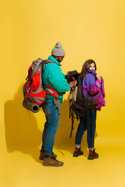 Portrait of a cheerful young tourist couple isolated on yellow background - Fotoğraf, Görsel
