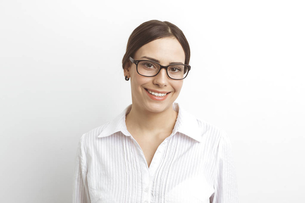 Όμορφη χαμογελαστή νεαρή γυναίκα με γυαλιά σε λευκό φόντο. - Φωτογραφία, εικόνα
