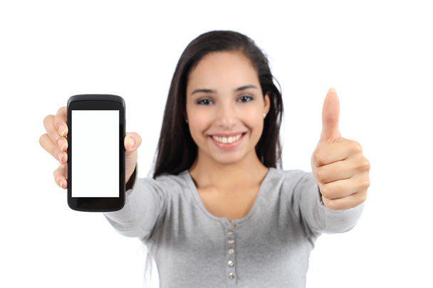 Pretty smiling woman showing a blank vertical smart phone screen and thumb up isolated - Fotó, kép