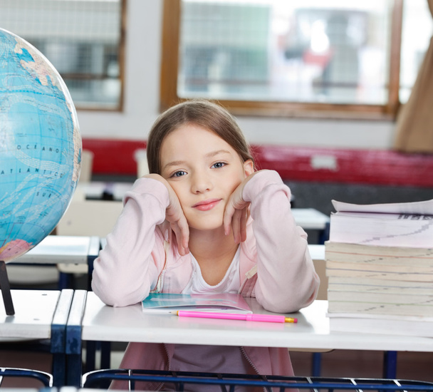 Écolière avec pile de livres et globe au bureau
 - Photo, image