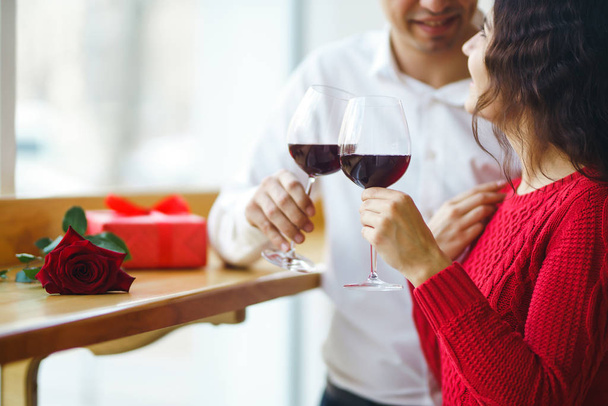 Young couple having a romantic dinner and toasting with glass of red wine. Sweet couple celebrate their anniversary. Valentine's Day, holiday concept. Relationship, surprise and love concept. - Фото, зображення