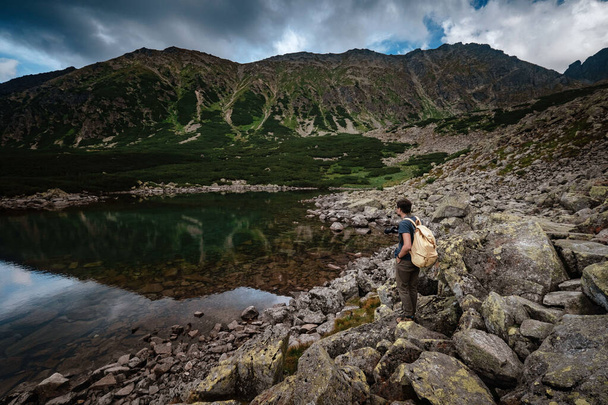Mężczyzna Podróżnik z plecakiem w pobliżu jeziora górskiego - Zdjęcie, obraz