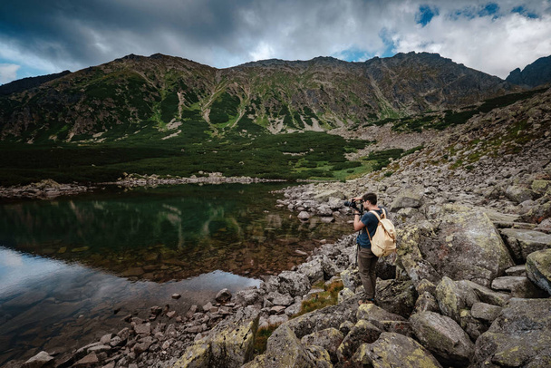 Mężczyzna Podróżnik z plecakiem w pobliżu jeziora górskiego - Zdjęcie, obraz