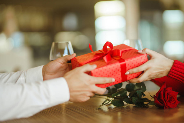 Valentine's Day, holiday and surprise concept. Man gives to his woman a red gift box. Sweet couple celebrate their anniversary. Relationship and love concept. - Φωτογραφία, εικόνα