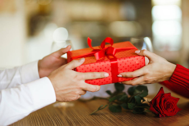 Valentine's Day, holiday and surprise concept. Man gives to his woman a red gift box. Sweet couple celebrate their anniversary. Relationship and love concept. - Фото, изображение