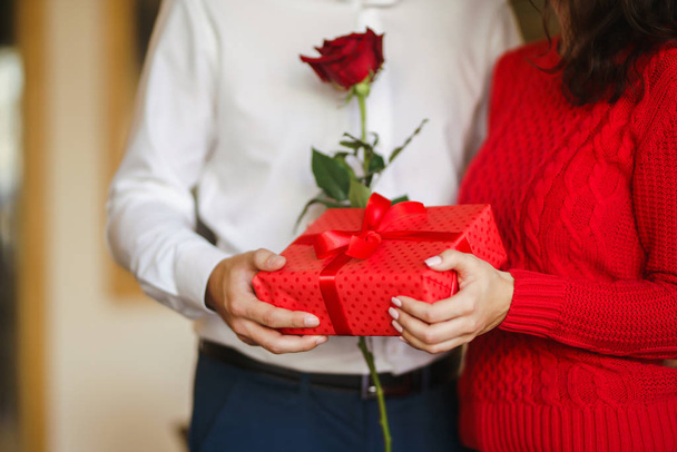 Valentine's Day, holiday and surprise concept. Man gives to his woman a red gift box. Sweet couple celebrate their anniversary. Relationship and love concept. - Foto, Imagen