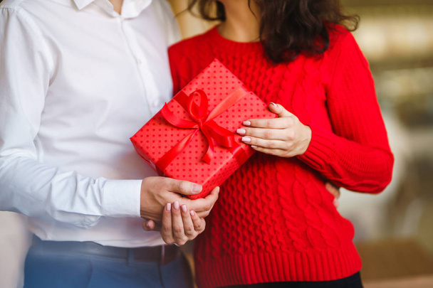 Valentine's Day, holiday and surprise concept. Man gives to his woman a red gift box. Sweet couple celebrate their anniversary. Relationship and love concept. - Zdjęcie, obraz