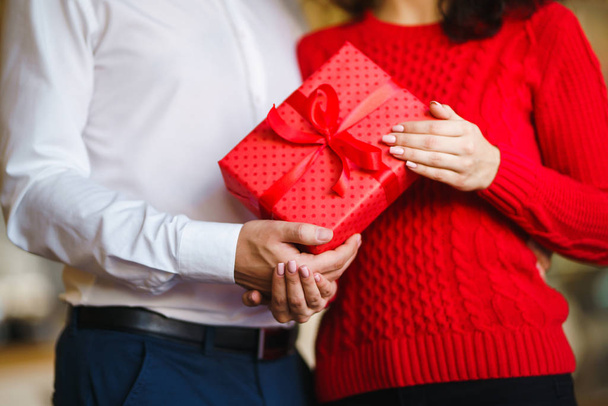 Valentine's Day, holiday and surprise concept. Man gives to his woman a red gift box. Sweet couple celebrate their anniversary. Relationship and love concept. - Fotografie, Obrázek