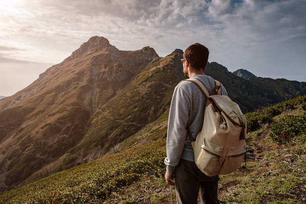 Nuori mies seisoo kalliolla vuorilla
 - Valokuva, kuva
