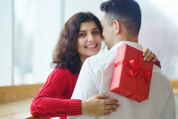 Happy couple with gift hugging. Red gift box in the hands of a couple in love. Valentine's Day, holiday and surprise concept. Lovers give each other presents. Relationship and love concept. - Фото, зображення