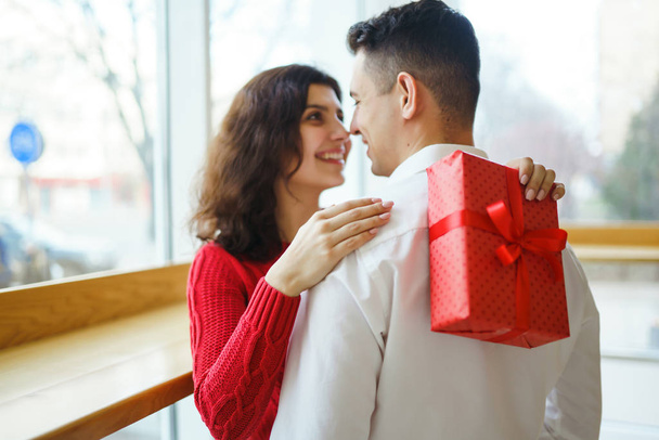 Happy couple with gift hugging. Red gift box in the hands of a couple in love. Valentine's Day, holiday and surprise concept. Lovers give each other presents. Relationship and love concept. - Fotó, kép
