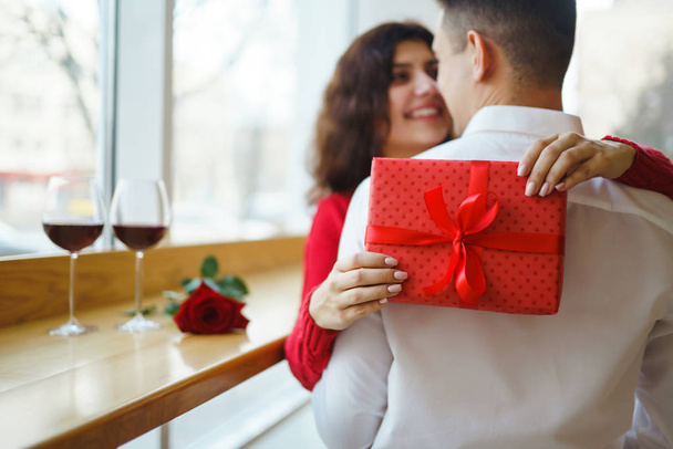 Happy couple with gift hugging. Red gift box in the hands of a couple in love. Valentine's Day, holiday and surprise concept. Lovers give each other presents. Relationship and love concept. - Foto, afbeelding