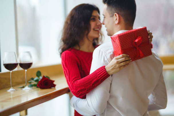 Happy couple with gift hugging. Red gift box in the hands of a couple in love. Valentine's Day, holiday and surprise concept. Lovers give each other presents. Relationship and love concept. - Foto, Imagem