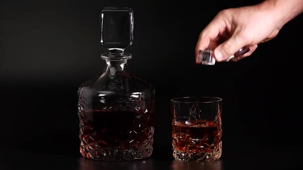 Rövidfilm, amin whiskyt öntenek egy pohárba, jéggel, fekete háttérrel. Lassú mozgás. Gyönyörű háttér. Az alkohol fogalma. - Felvétel, videó
