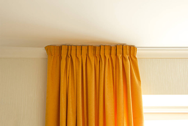 sun filled room with yellow curtains hunging on a rod - Photo, Image
