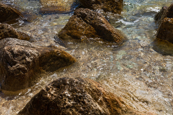 волна катится по большим камням на пляже
 - Фото, изображение