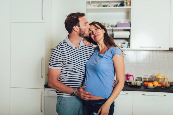 вагітна жінка з чоловіком на кухні
 - Фото, зображення