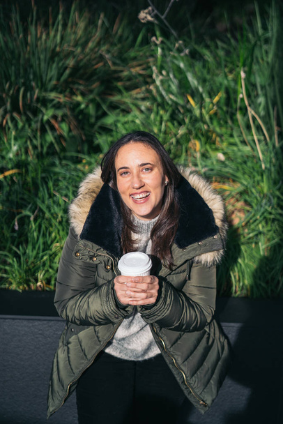 Young woman smiling holding a hot coffee in paper cup in Sky Garden London. - Foto, Imagen