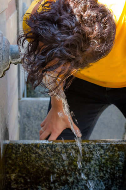 Brunette femme eau potable à partir du bec d'une fontaine
 - Photo, image