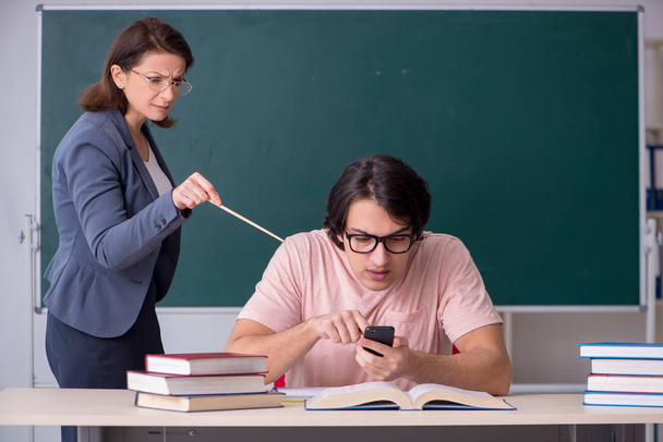 Old female teacher and male student in the classroom - Photo, Image