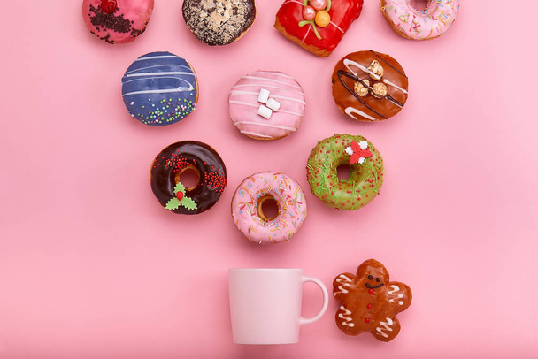 Donuts coloridos con glaseado y tazas de café sobre fondo rosa pastel. Rosquillas dulces
. - Foto, imagen